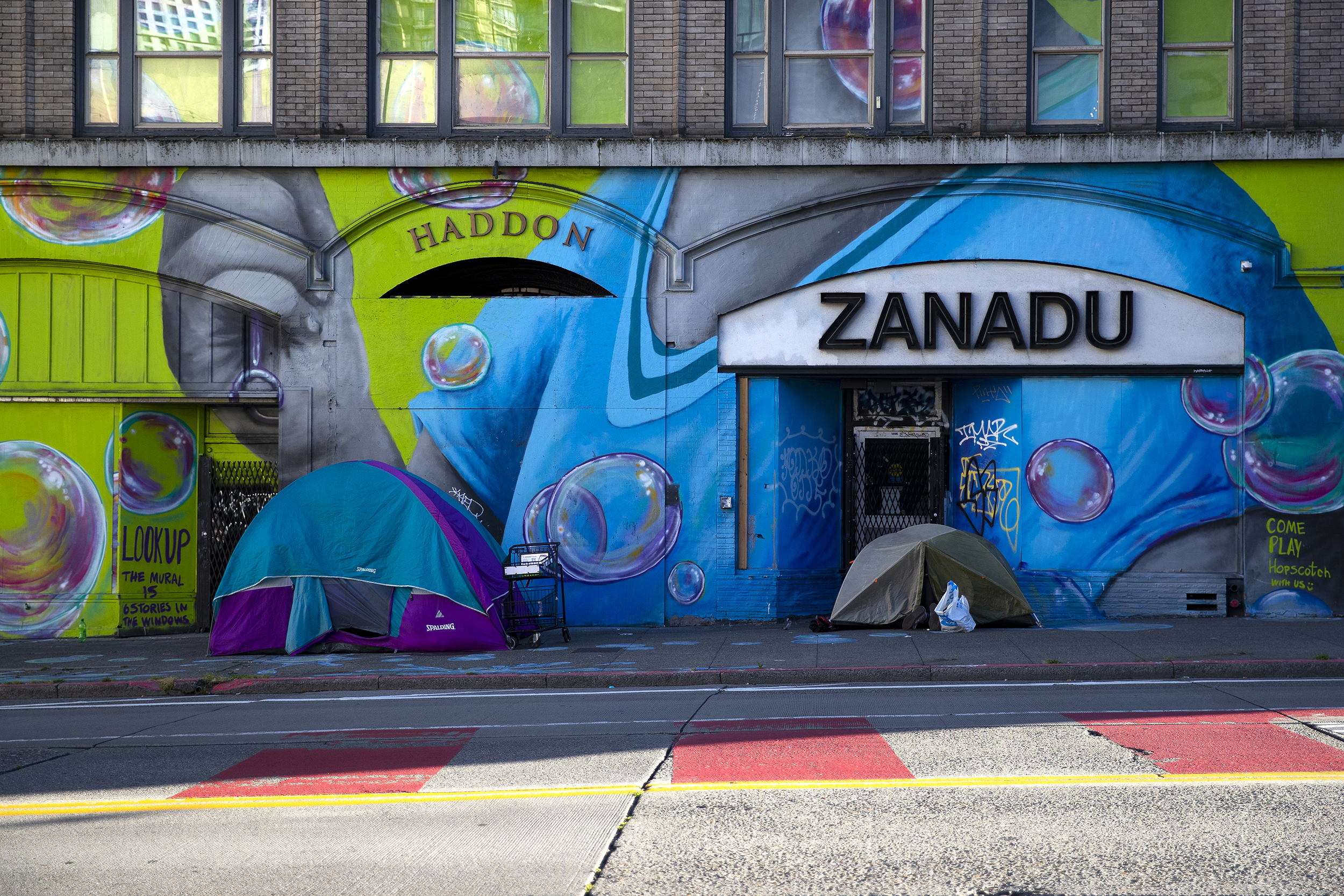 caption: People shelter themselves in tents along 3rd Avenue on Tuesday, July 1, 2025, in Seattle, Washington. 