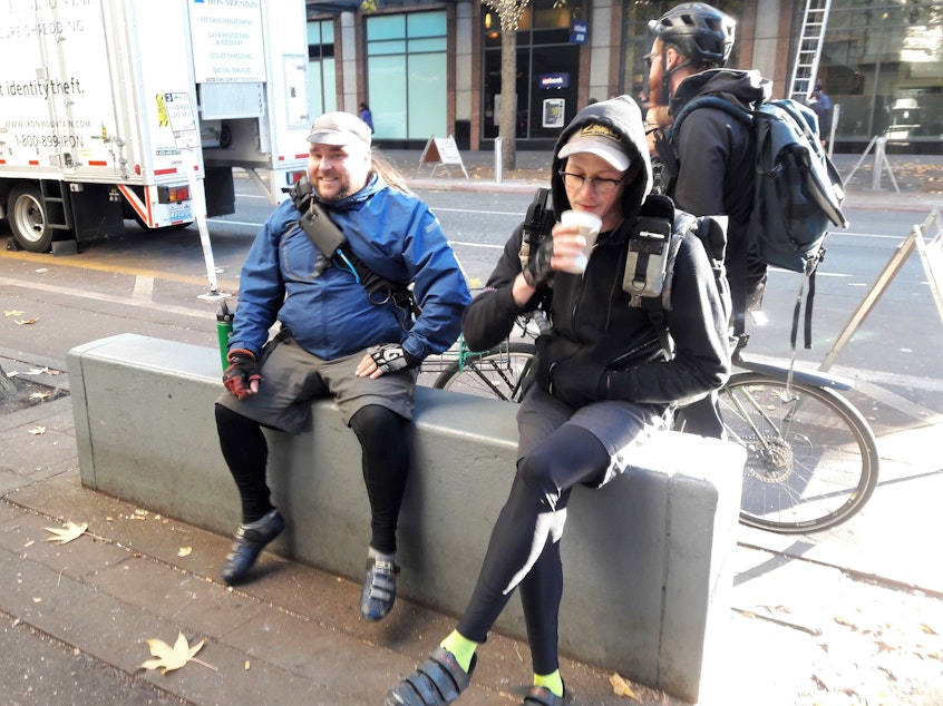 caption: Bicycle couriers say they will do just fine. “We’ll probably get called a lot during it because you can’t – you’re not going to be able to get out of the city,”  said Jory Wallis, left, beside Kevin Shinn. They both work for Seattle Messenger Cooperative.