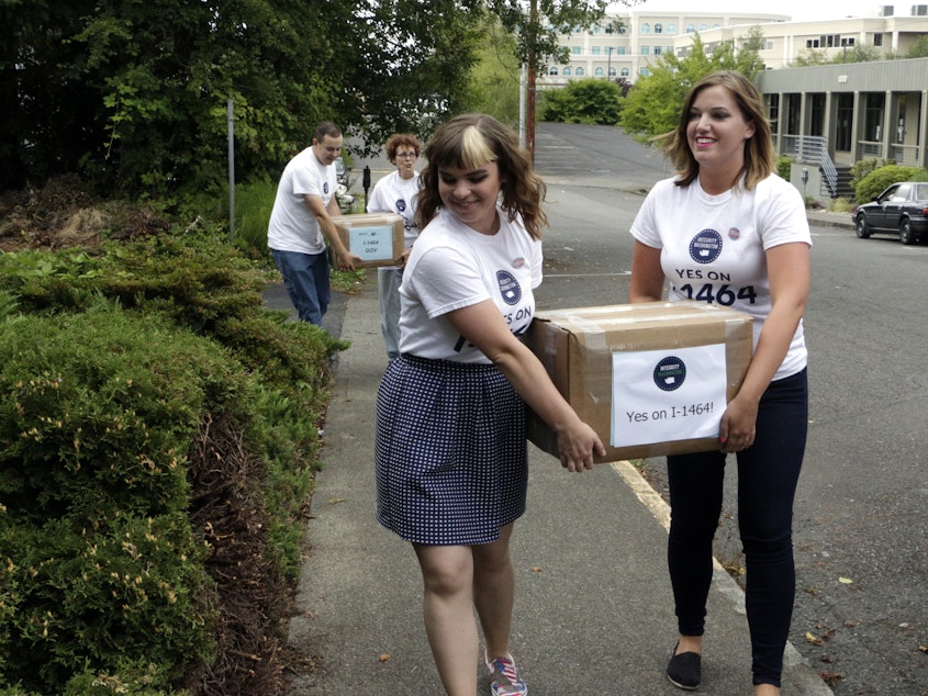 caption: File photo: Supporters of a proposed campaign finance reform ballot initiative carry boxes of signed petitions to turn in, on July 8, 2016, in Olympia.