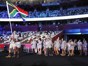caption: Flag bearers Phumelela Luphumlo Mbande and Chad Le Clos of Team South Africa lead their team out during the opening ceremony of the Tokyo Olympic Games on Friday.