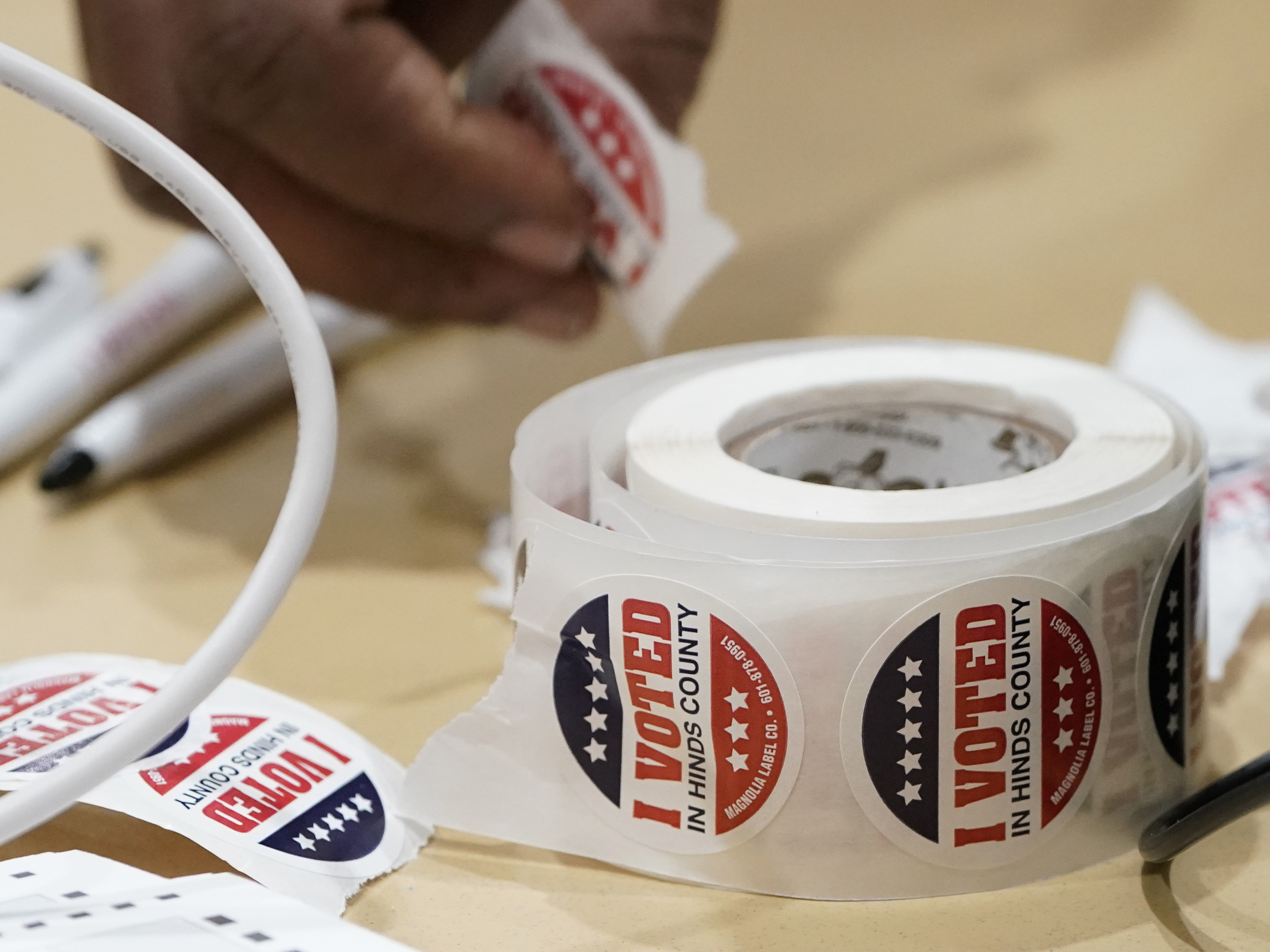 caption: A precinct worker reaches for more "I Voted" stickers on Nov. 7 in Jackson, Miss. A few polling places in Jackson's Hinds County saw ballot shortages during this year's statewide general election, frustrating voters.