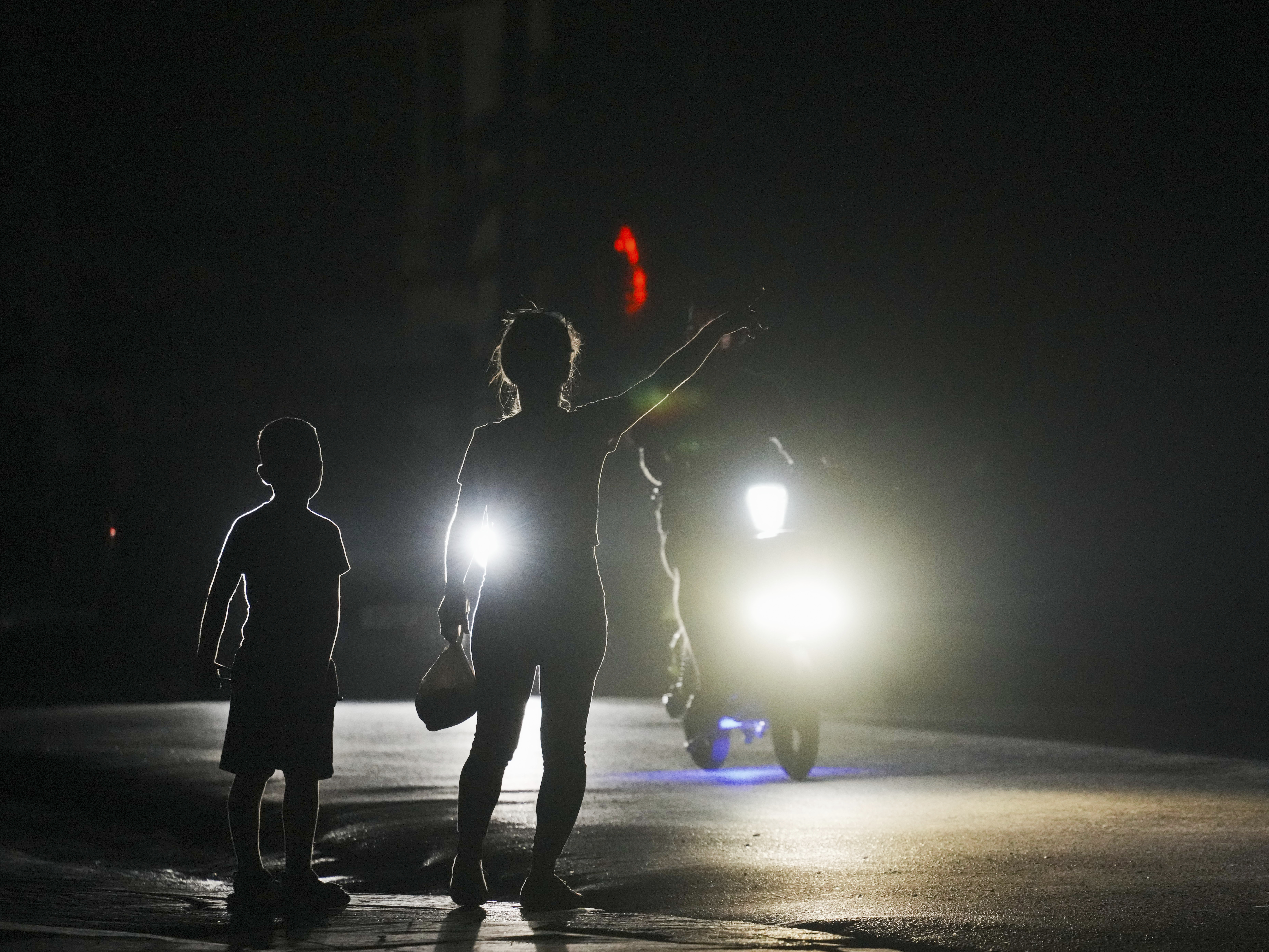 caption: A woman and a boy attempt to hitch a ride during a scheduled power outage in Bauta, Cuba, Monday. The island is facing an energy crisis, with waves of blackouts worsening in recent weeks.