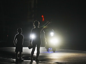 caption: A woman and a boy attempt to hitch a ride during a scheduled power outage in Bauta, Cuba, Monday. The island is facing an energy crisis, with waves of blackouts worsening in recent weeks.