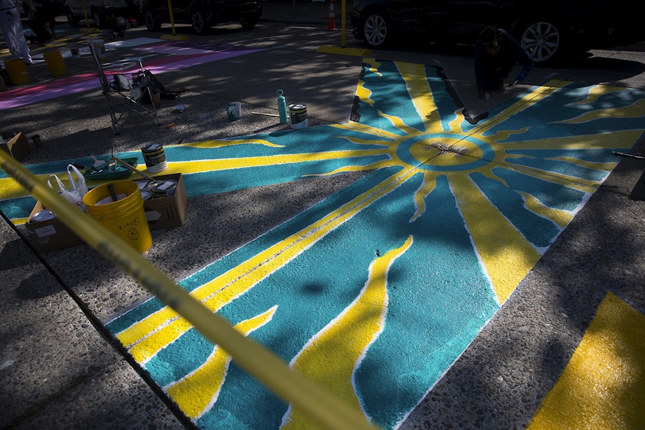 caption: Local artist Ari paints the letter K in the Black Lives Matter street mural on Friday, October 2, 2020, on E. Pine Street in Seattle.