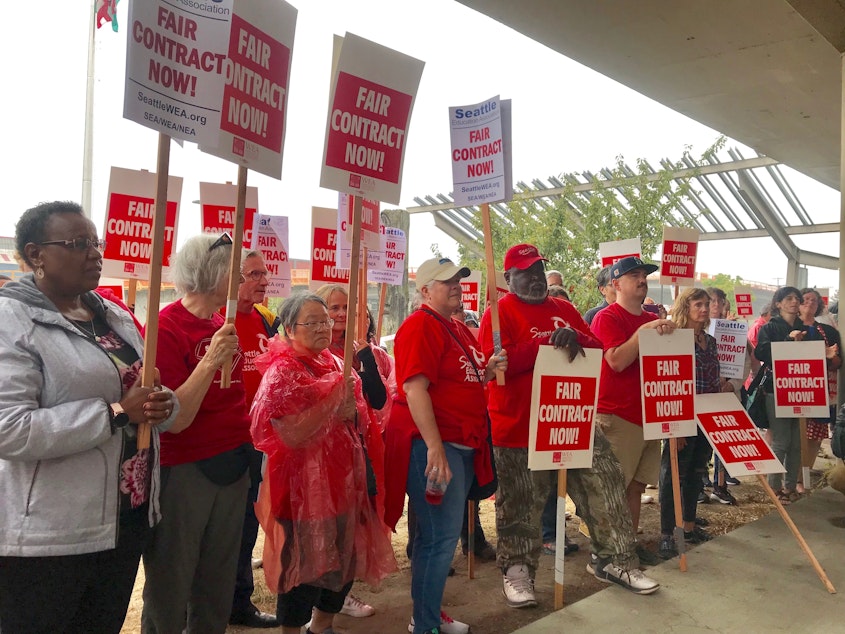 caption: Members of Seattle's teachers union, the Seattle Education Association, rally outside district headquarters on August 21, 2019.