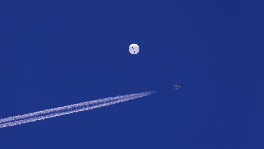 caption: A fighter jet flies near a large balloon drifting above the Atlantic Ocean, just off the coast of South Carolina near Myrtle Beach, Saturday, Feb. 4, 2023. Minutes later, the balloon was struck by a missile from an F-22 fighter jet, ending its weeklong traverse over the U.S. China said the balloon was a weather research vessel blown off course, a claim rejected by U.S. officials. 