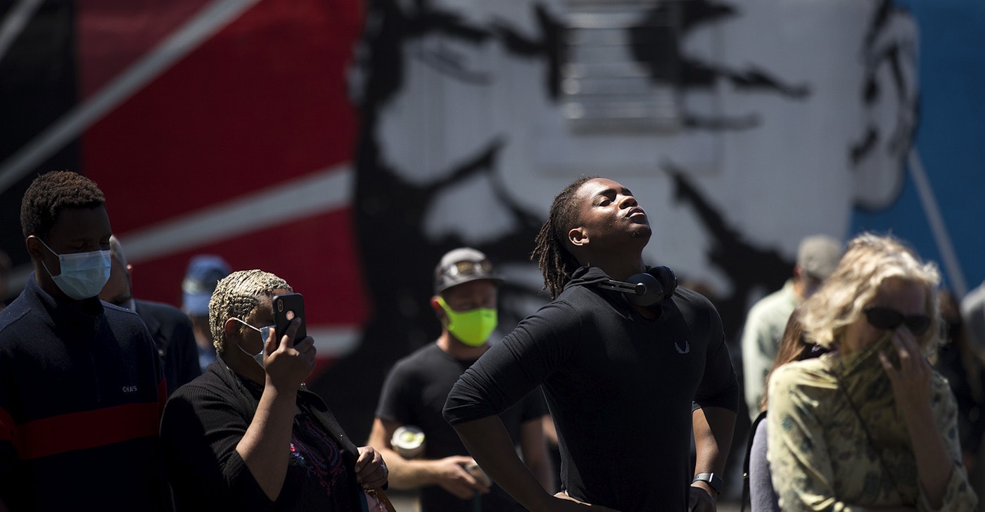 caption: Hanz Jouissance, center, stands in front of a mural of Dr. Martin Luther King Jr. while attending a vigil to recognize the senseless killing of African American men and women outside of the First African Methodist Episcopal Church on Monday, June 1, 2020, in Seattle.