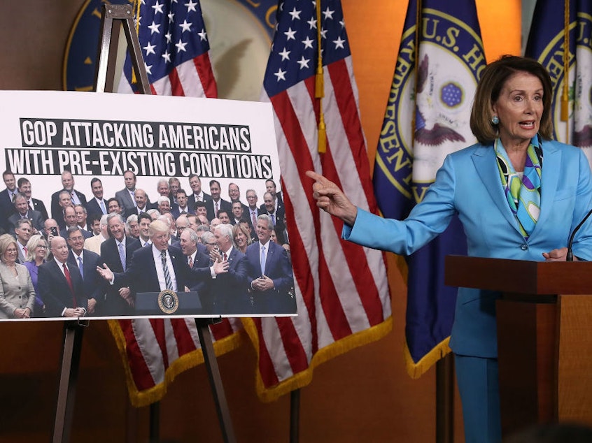 caption: Democratic Minority Leader Nancy Pelosi, D-Calif., speaks about health care as she points to a picture of President Trump with House GOP members during her weekly news conference on Capitol Hill in June.