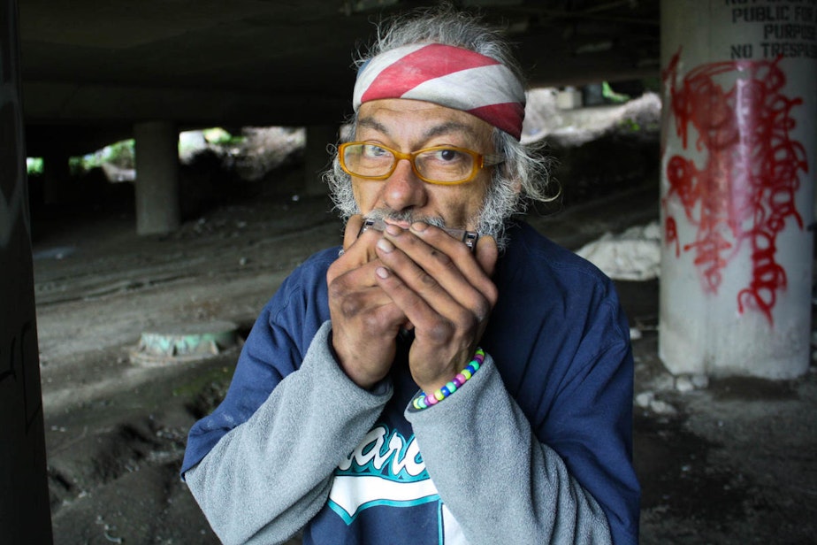 caption: Jacobo Miguel Pinon Jr. plays the harmonica at his space in the Jungle, a homeless encampment that houses more than 400 people by some estimates.