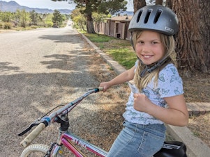 caption: The author's 8-year-old daughter Rosy has a 'kids' license,' showing she has her parents' permission to ride her bike around her Texas hometown.