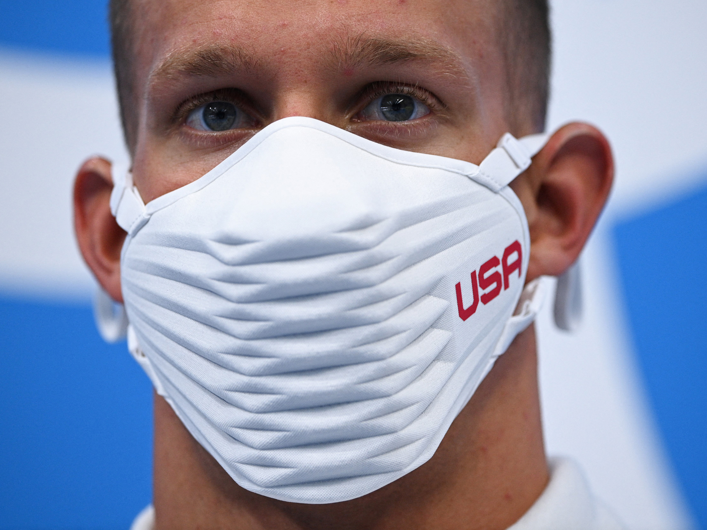 caption: Team USA's Caeleb Dressel wears a USA-branded face covering while waiting to receive his gold medal after the final of the men's 4x100 meter freestyle relay swimming event during the Tokyo Olympics at the Tokyo Aquatics Centre on Monday.