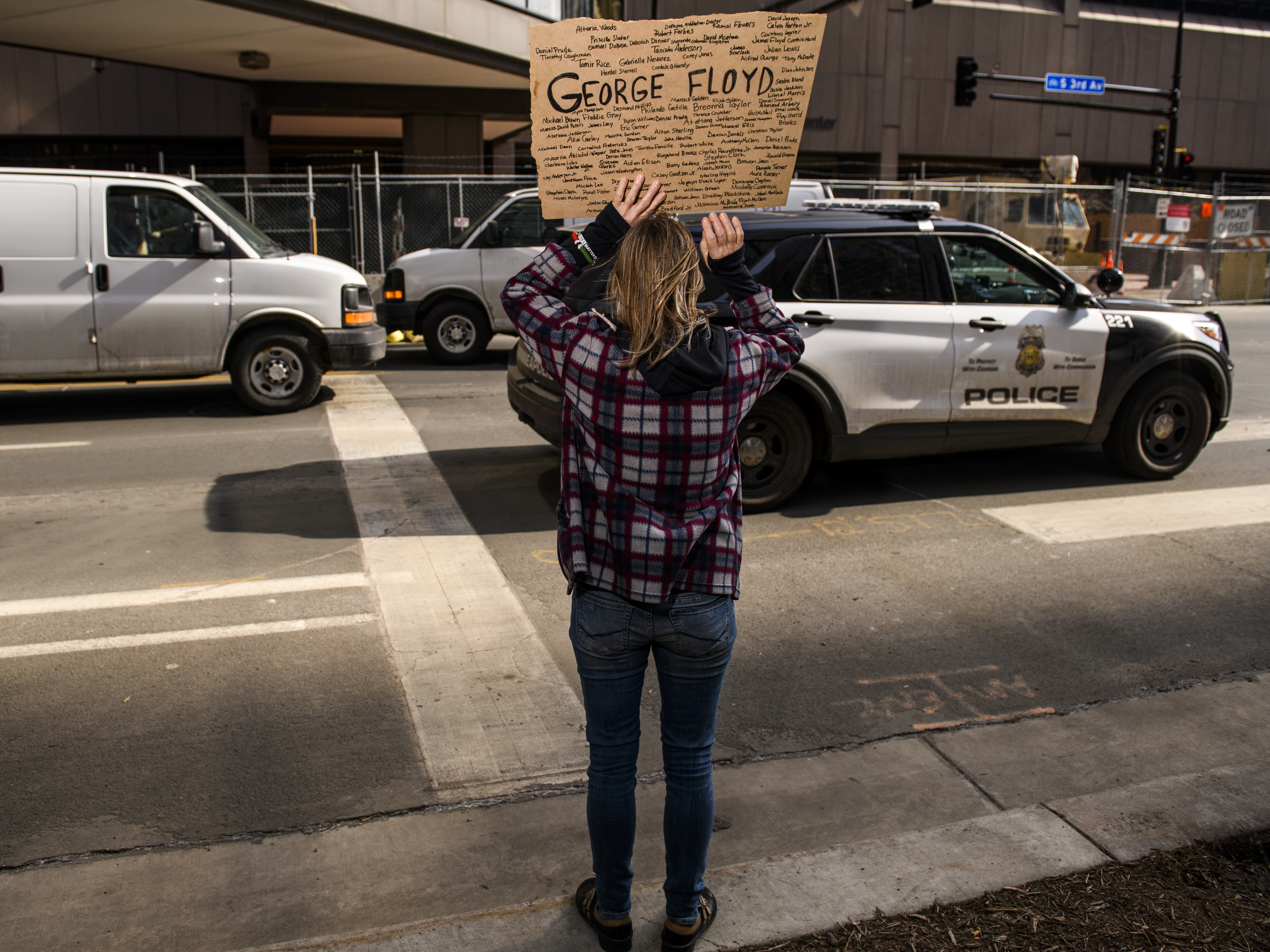 caption: A Minneapolis Police cruiser drives by as people demonstrate outside the Hennepin County Government Center on March 9, 2021 in Minneapolis.