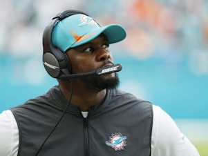 caption: Former head coach Brian Flores of the Miami Dolphins looks on from the side line during the game against the New York Jets at Hard Rock Stadium on Dec. 19, 2021 in Miami Gardens, Fla.