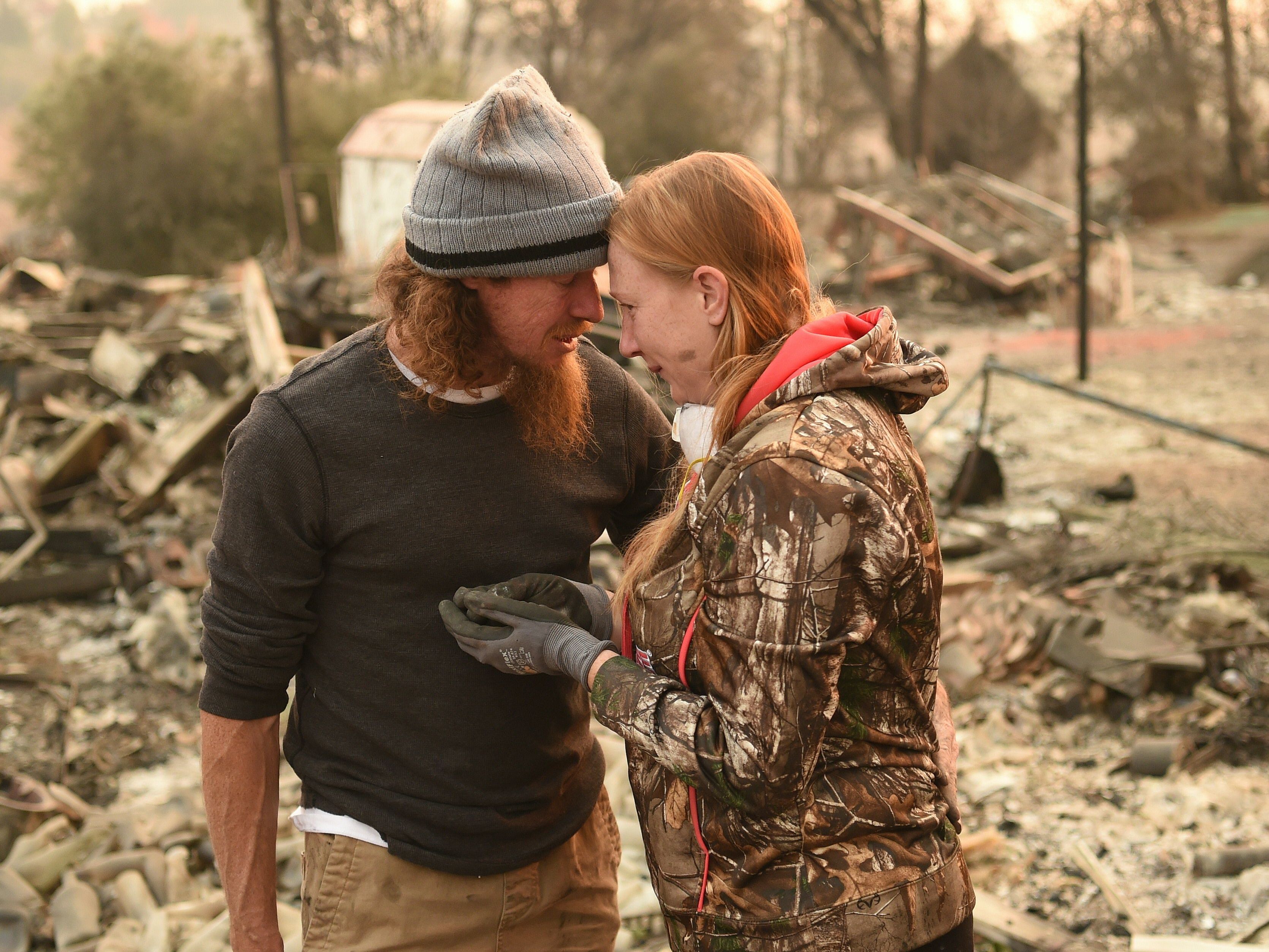 caption: Ryan Spainhower and his wife Kimberly discover a coin they had made during their honeymoon amidst the burned ashes of their home in Paradise, Calif., on Sunday.