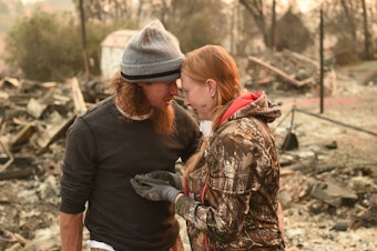 caption: Ryan Spainhower and his wife Kimberly discover a coin they had made during their honeymoon amidst the burned ashes of their home in Paradise, Calif., on Sunday.