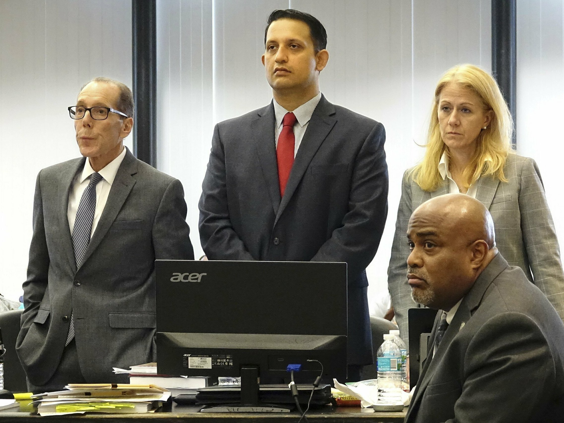caption: Nouman Raja (center) stands with his defense team at his trial in West Palm Beach, Fla. Raja, a former Palm Beach Gardens police officer, was convicted for shooting and killing stranded motorist Corey Jones in 2015.