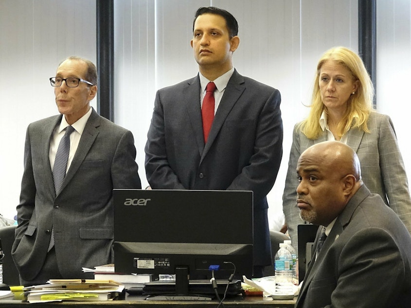 caption: Nouman Raja (center) stands with his defense team at his trial in West Palm Beach, Fla. Raja, a former Palm Beach Gardens police officer, was convicted for shooting and killing stranded motorist Corey Jones in 2015.