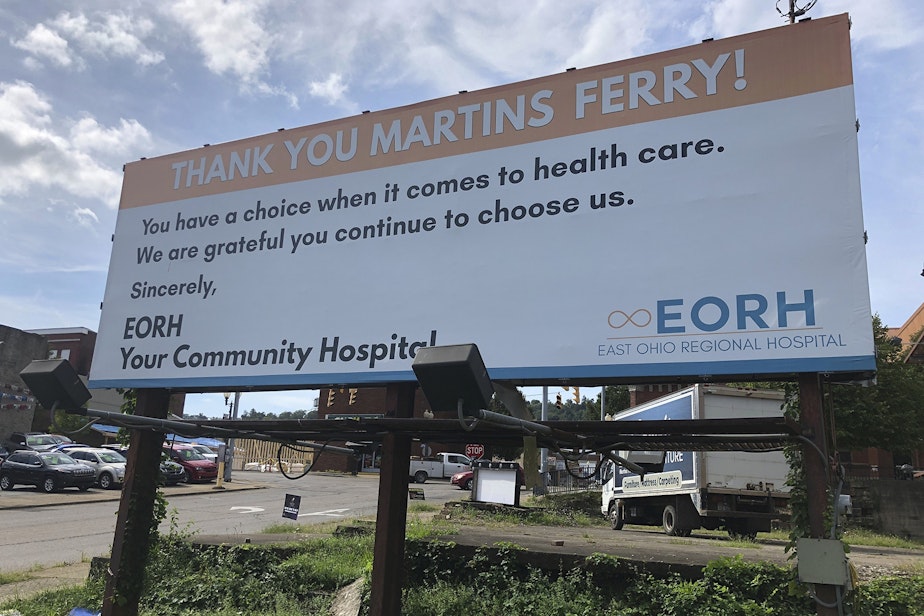 caption: A billboard from East Ohio Regional Hospital is shown Tuesday, Sept. 3, 2019, in Martins Ferry, Ohio. The hospital and sister facility Ohio Valley Medical Center in Wheeling, W.Va., are closing after two years of ownership by Irvine, California-based Alecto Healthcare Services. (John Raby/AP)