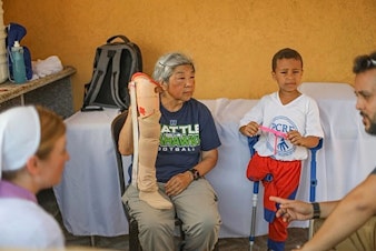 caption: Ramona Okumura, center, with a prosthetic leg for a child. 