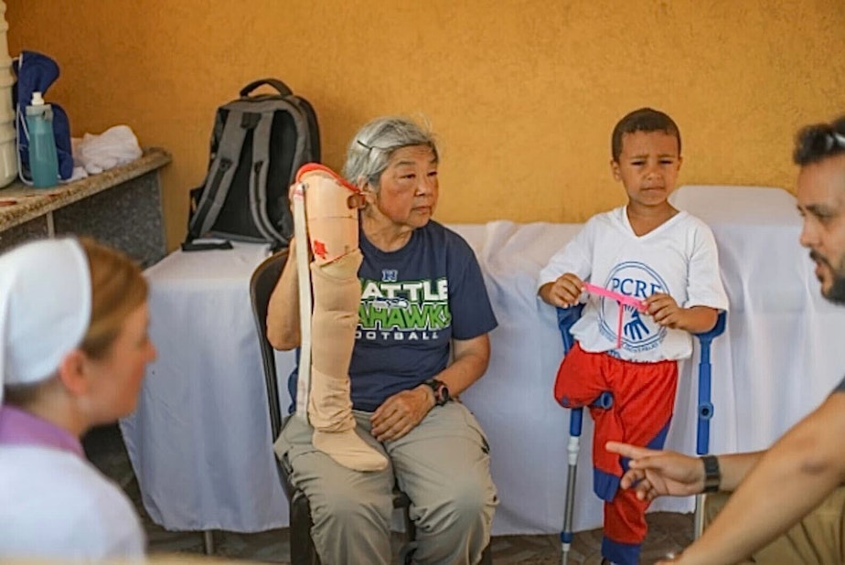 caption: Ramona Okumura, center, with a prosthetic leg for a child. 