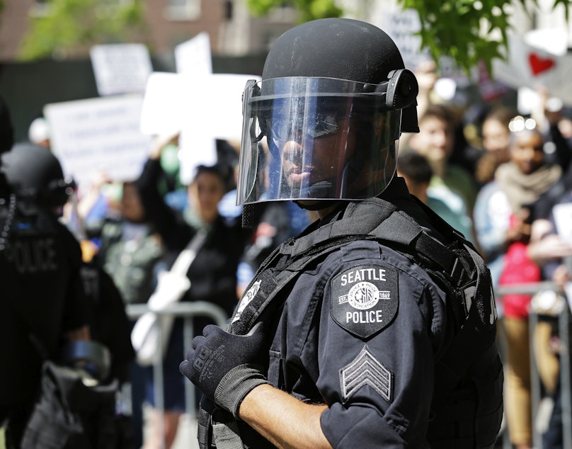 caption: A Seattle Police officer watches counter-protesters as they stand behind barricades across the street from an anti-Islamic law rally Saturday, June 10, 2017, in Seattle.