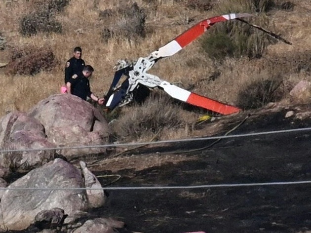 caption: Investigators walk around rotor blades from a crashed helicopter on a burned hillside in Cabazon, Calif., on Monday, Aug. 7, 2023. Three people were killed when their helicopter crashed into a hillside after colliding with another chopper as the team battled a wildfire, emergency officials said. (Photo by Patrick T. Fallon / AFP via Getty Images)