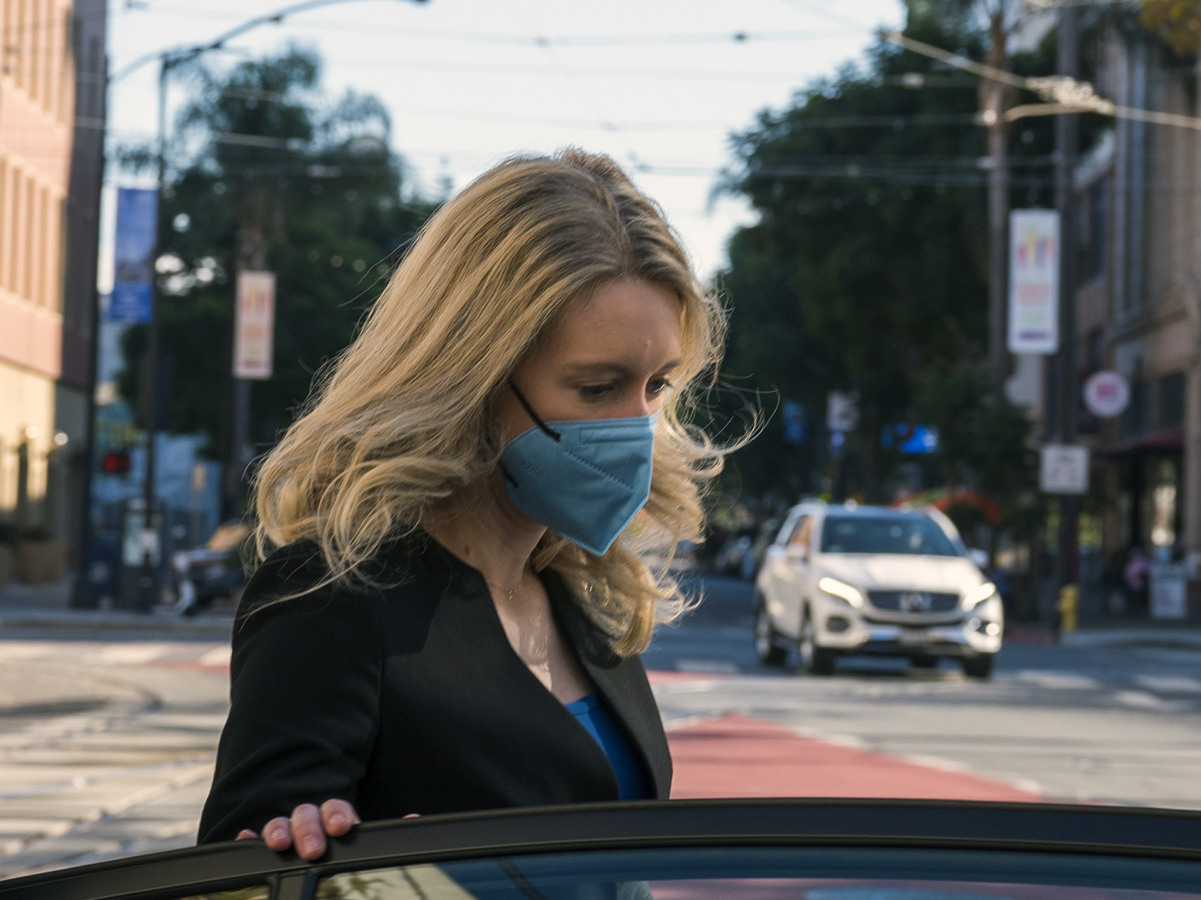 caption: Elizabeth Holmes, center, leaves federal court in San Jose, Calif., on Nov. 22. The one-time medical entrepreneur now charged with building a fraudulent company based on promises of a revolutionary technology returned to the witness stand Monday.