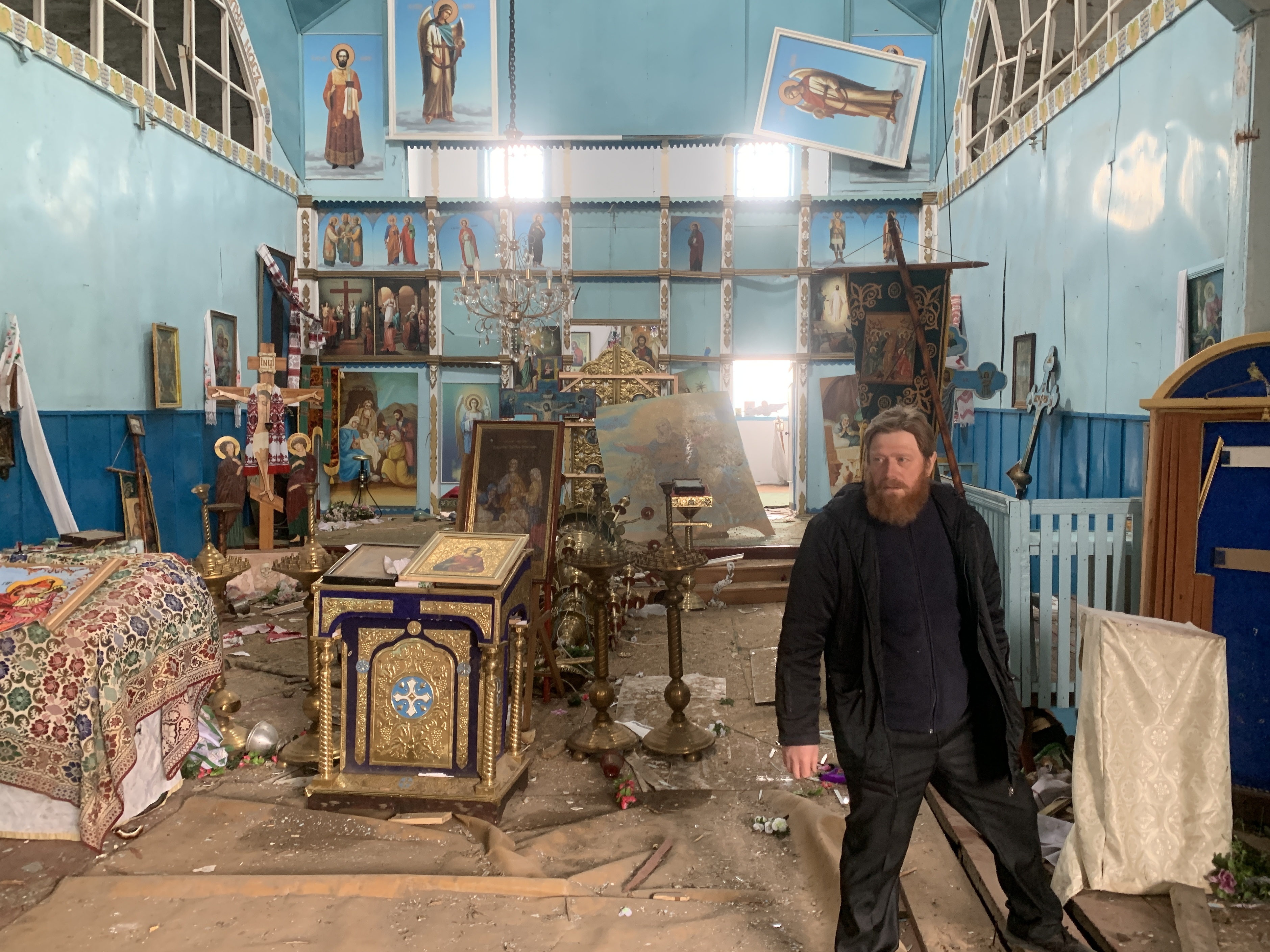 caption: Father Oleksandr Yarmolchyk stands inside the demolished nave of his Orthodox church in Peremoha, Ukraine on April 17. He says the Russians bombed his church and held him against his will.