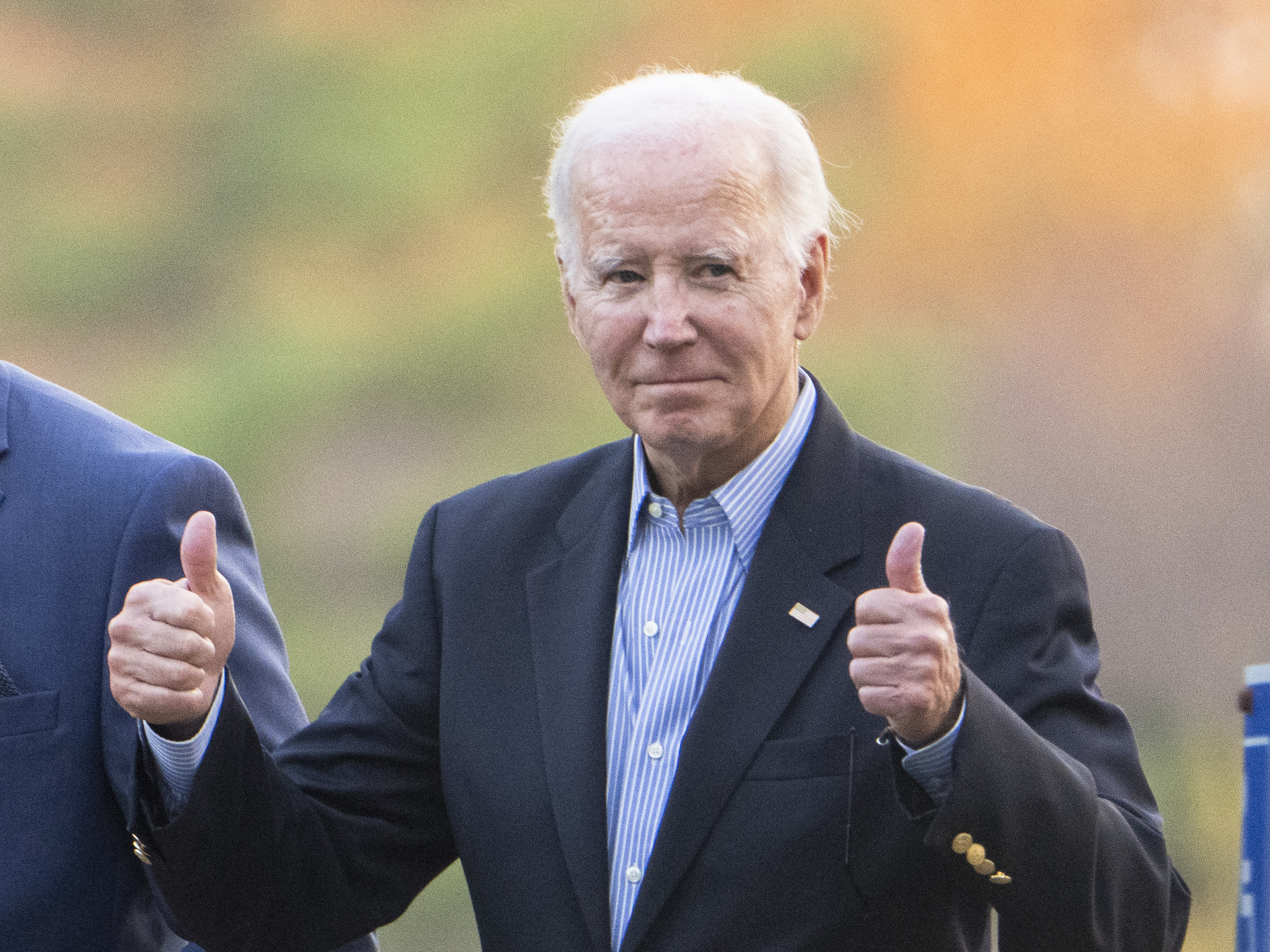 caption: President Biden gestures with two thumbs up responding to a question from the media about UAW deal as he leaves St. Joseph on the Brandywine Catholic Church in Wilmington, Del., on Oct. 28.