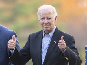 caption: President Biden gestures with two thumbs up responding to a question from the media about UAW deal as he leaves St. Joseph on the Brandywine Catholic Church in Wilmington, Del., on Oct. 28.