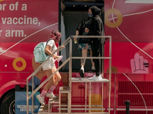 caption: A teenager enters a pop-up COVID-19 vaccine site this month in the Jackson Heights neighborhood of Queens in New York City.
