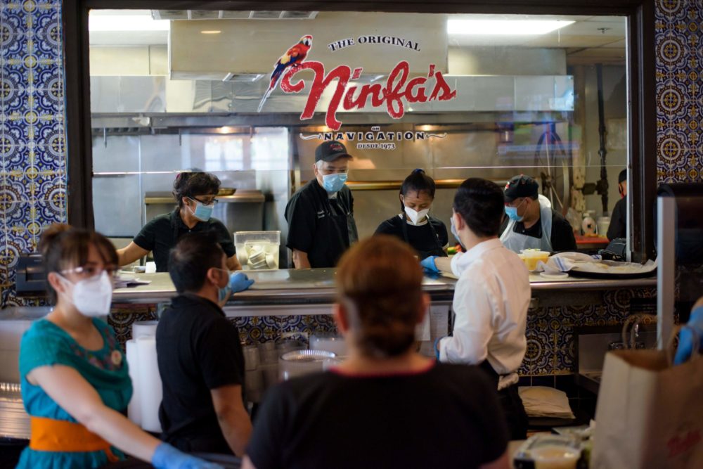 caption: Servers at The Original Ninfa's wear gloves and masks while bringing takeout orders to the kitche amid the novel coronavirus pandemic on May 1, 2020 in Houston, Texas. (Mark Felix/AFP)