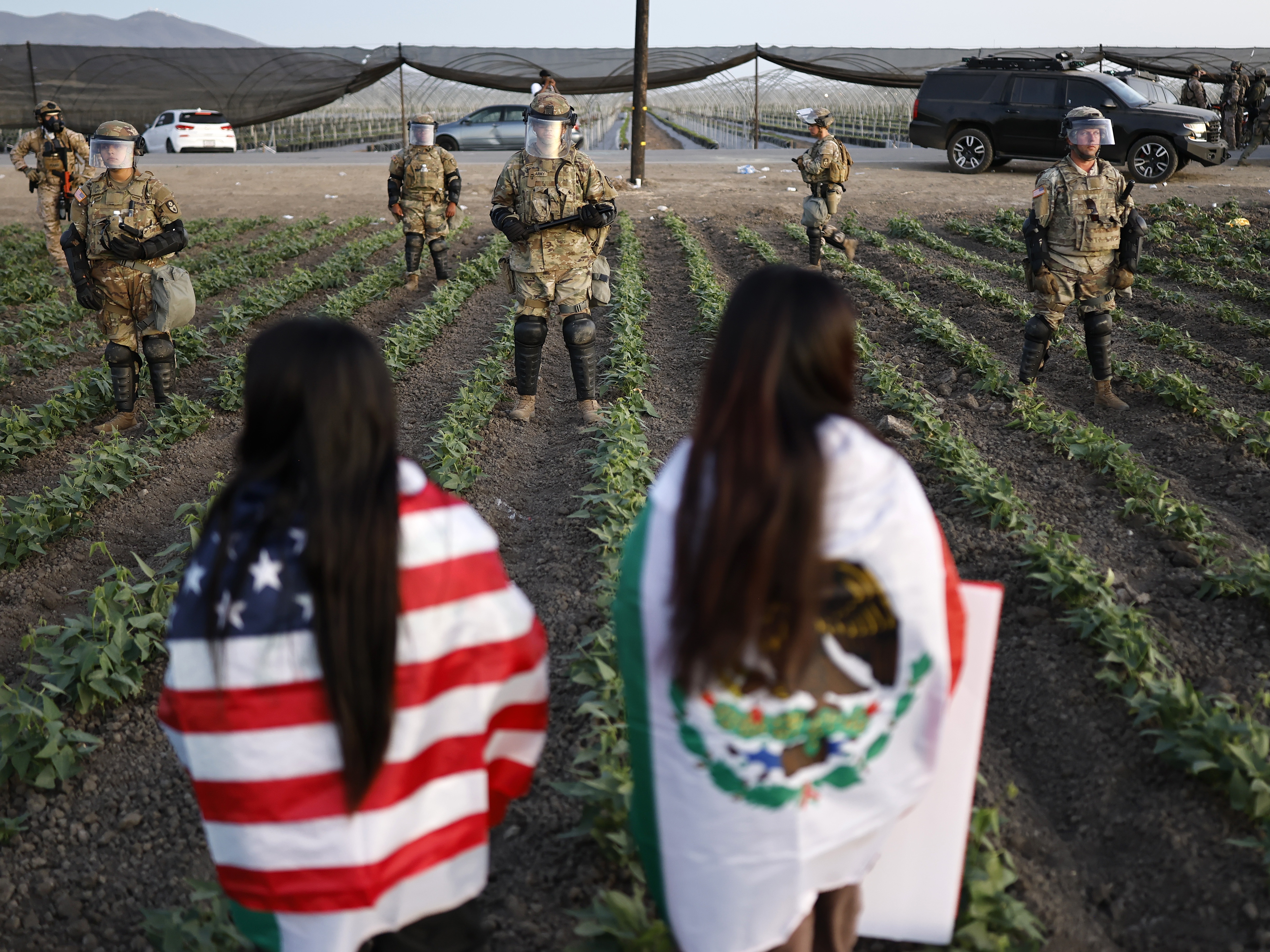 caption: National Guard soldiers block protesters during an ICE immigration raid at a cannabis farm on July 10 near Camarillo, California.