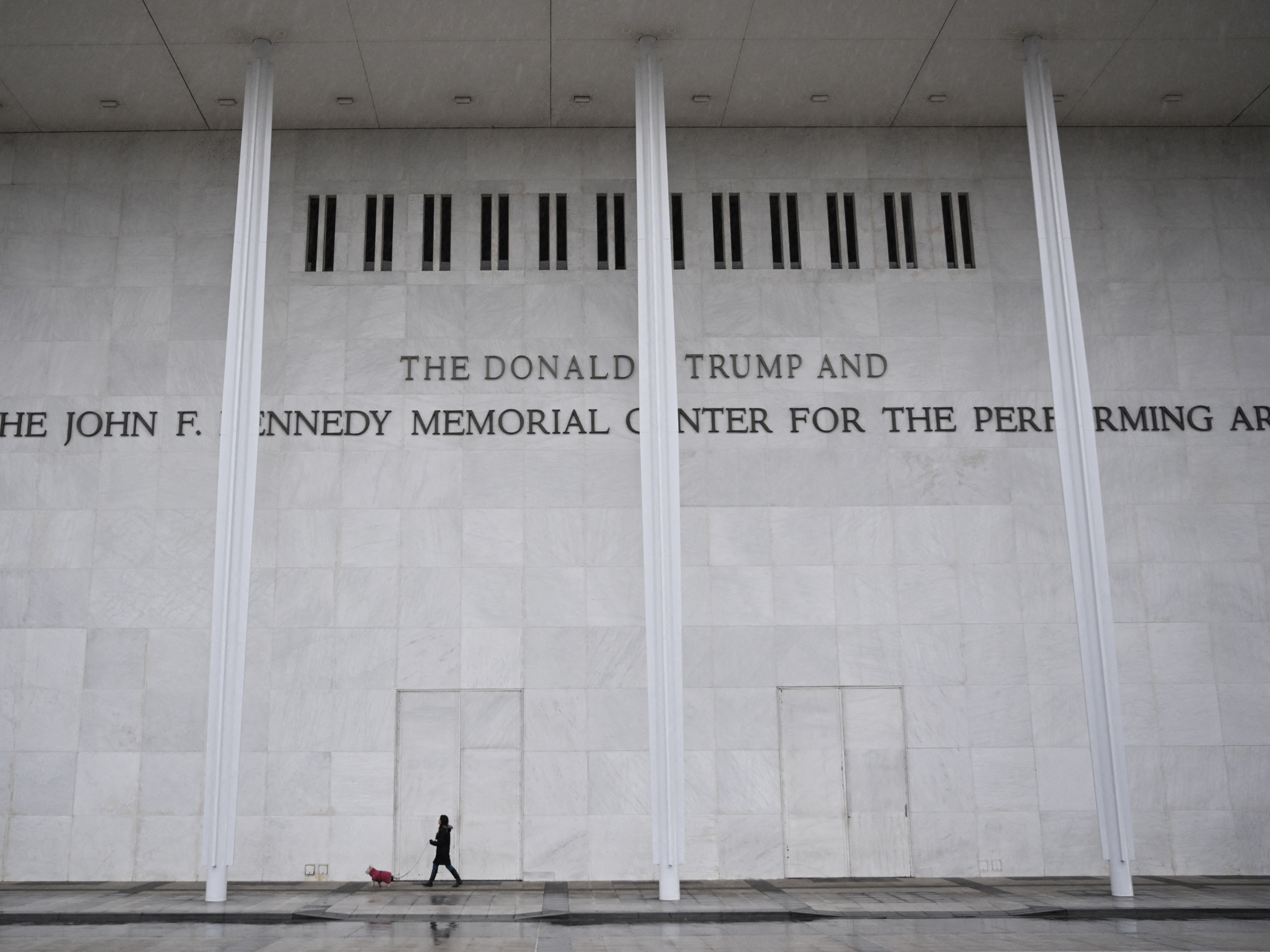 caption: A person walks a dog in front of the Kennedy Center in Washington, D.C., on Jan. 10, 2026.