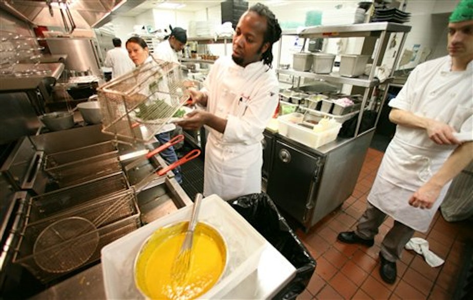 caption: Haitian immigrant Jean Emy Pierre, center, head chef at Colors, a restaurant co-owned by a multinational immigrant staff, with his kitchen staff as they prepare for dinner customers in New York.