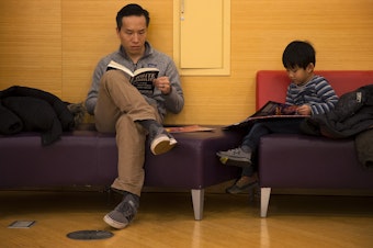 caption: Aintor Zeng, left, and Zach Zeng, 5, read at the Seattle Public Library Central branch on Thursday, January 2, 2020, on 4th Avenue in Seattle.