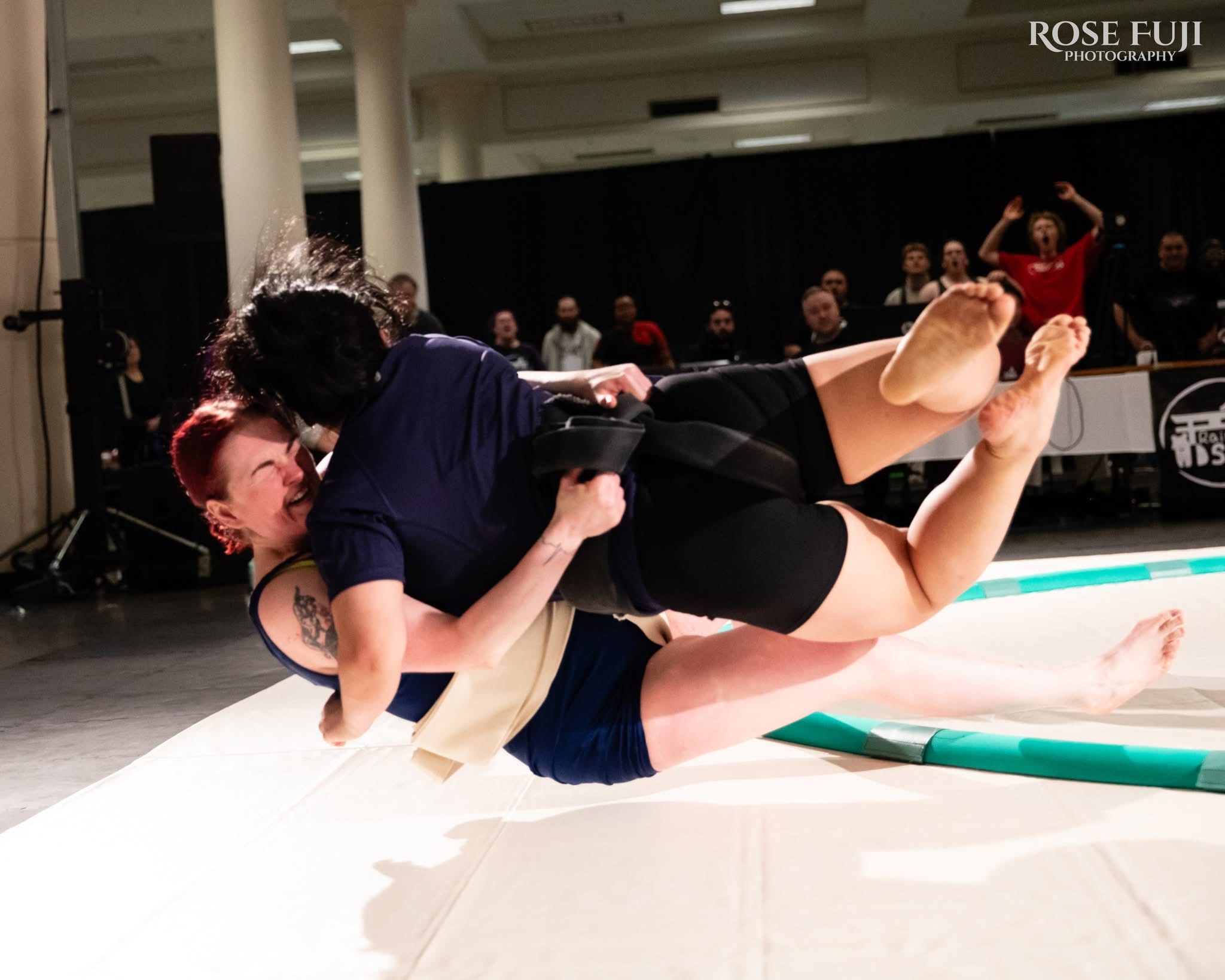 caption: Ailleen West throws a fellow Sumo wrestler out of the ring during the first annual Rain City Sumo Open in 2025.