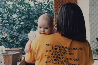 caption: Stephanie Hogan posing with her daughter while showing off her pro-woman, anti-apartheid shirt in Lanzhou, China, in May 1990. The text on the back of her T-shirt reads, "Now you have touched the women, you have struck a rock, you have dislodged a boulder, you will be crushed." 