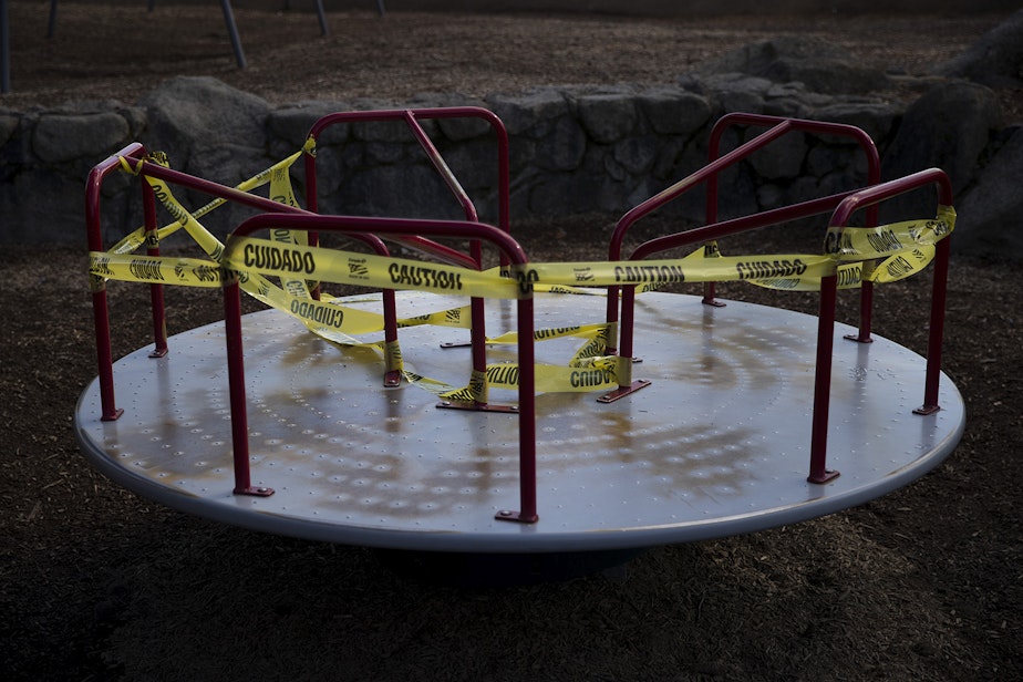 caption: A portion of a playground is off limits and surrounded by caution taped on Wednesday, March 25, 2020, at Seward Park in Seattle.