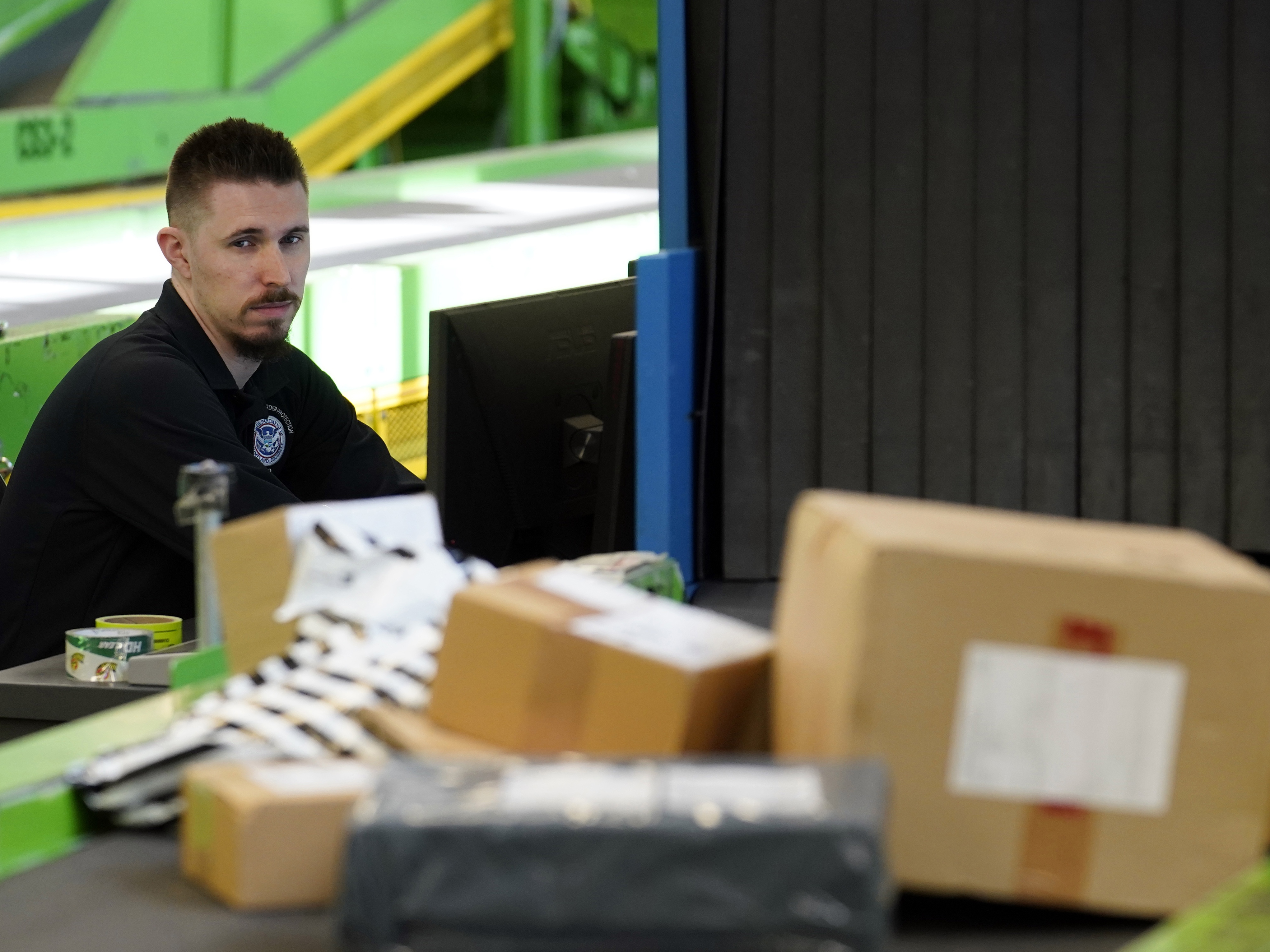caption: A U.S. Customs and Border Protection technician monitors overseas parcels as they get scanned at a mail inspection facility in Chicago.