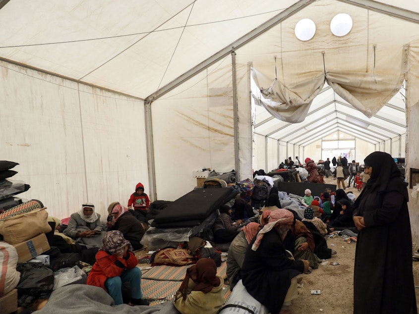caption: Displaced Syrians gather inside a tent in the Al-Hol camp in northeastern Syria in December.
