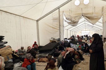 caption: Displaced Syrians gather inside a tent in the Al-Hol camp in northeastern Syria in December.