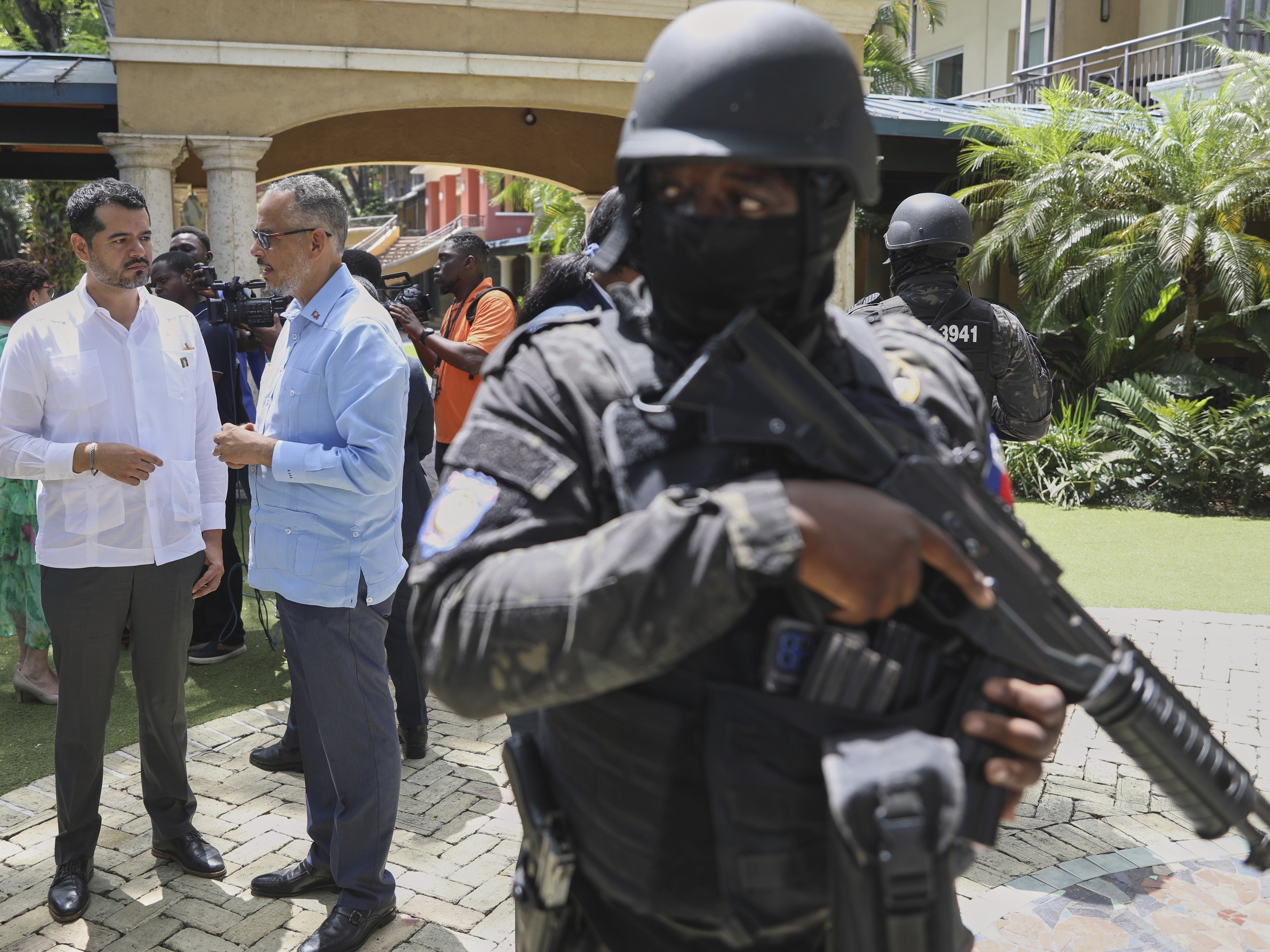 caption: Security guards stand watch as Haiti's Prime Minister Alix Didier Fils-Aime, center, talks with the Mexico's Charge d'Affaires Jesus Cisneros after attending an event marking one year since the start of the Multinational Security Support Mission in Port-au-Prince, Haiti on Thursday.
