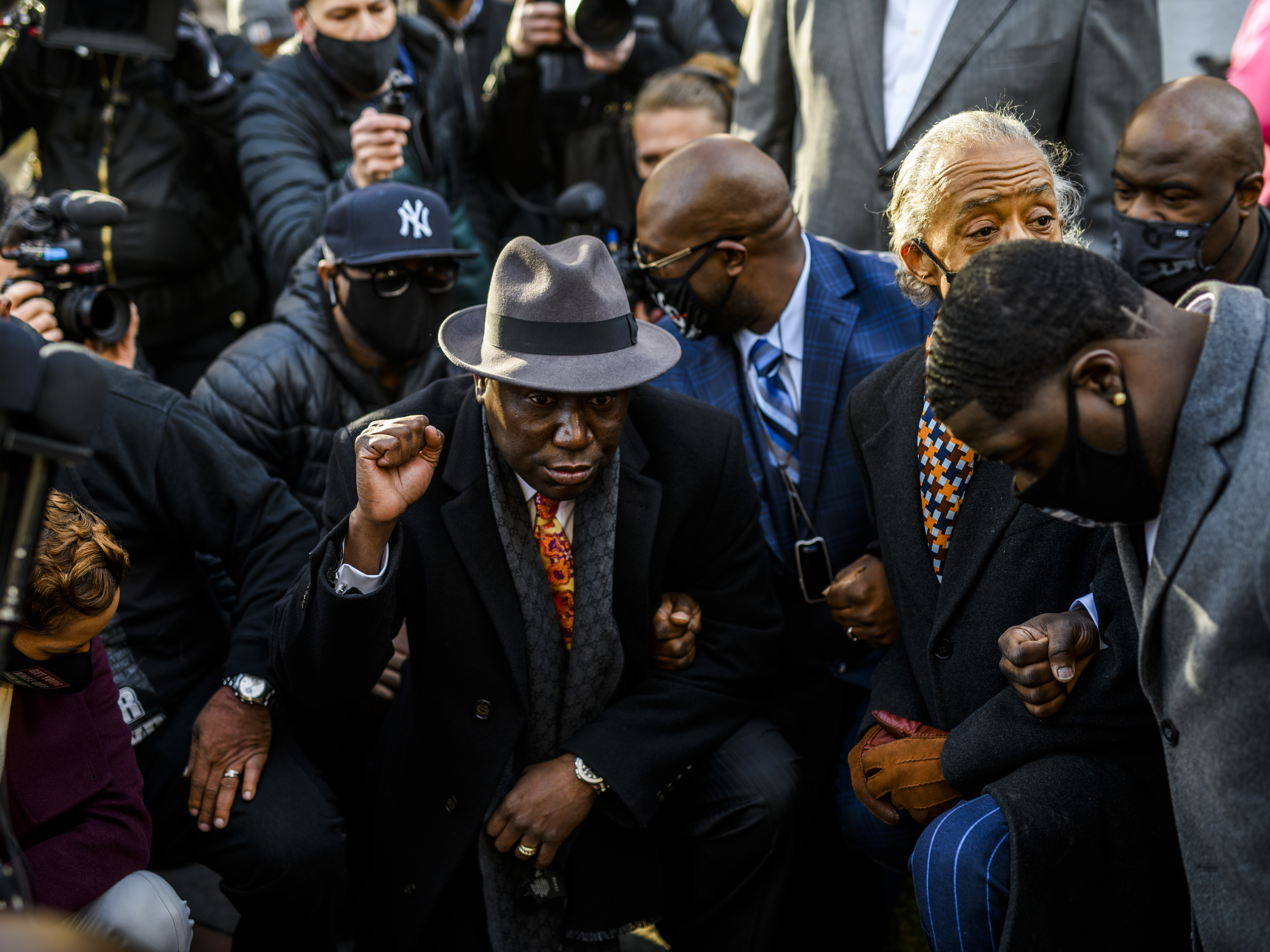 caption: Attorney Ben Crump (center) took a knee with members of George Floyd's family and Rev. Al Sharpton for 8 minutes and 46 seconds outside the Hennepin County Government Center in Minneapolis, Minn., on Monday, shortly before opening arguments began in the trial of former police officer Derek Chauvin.