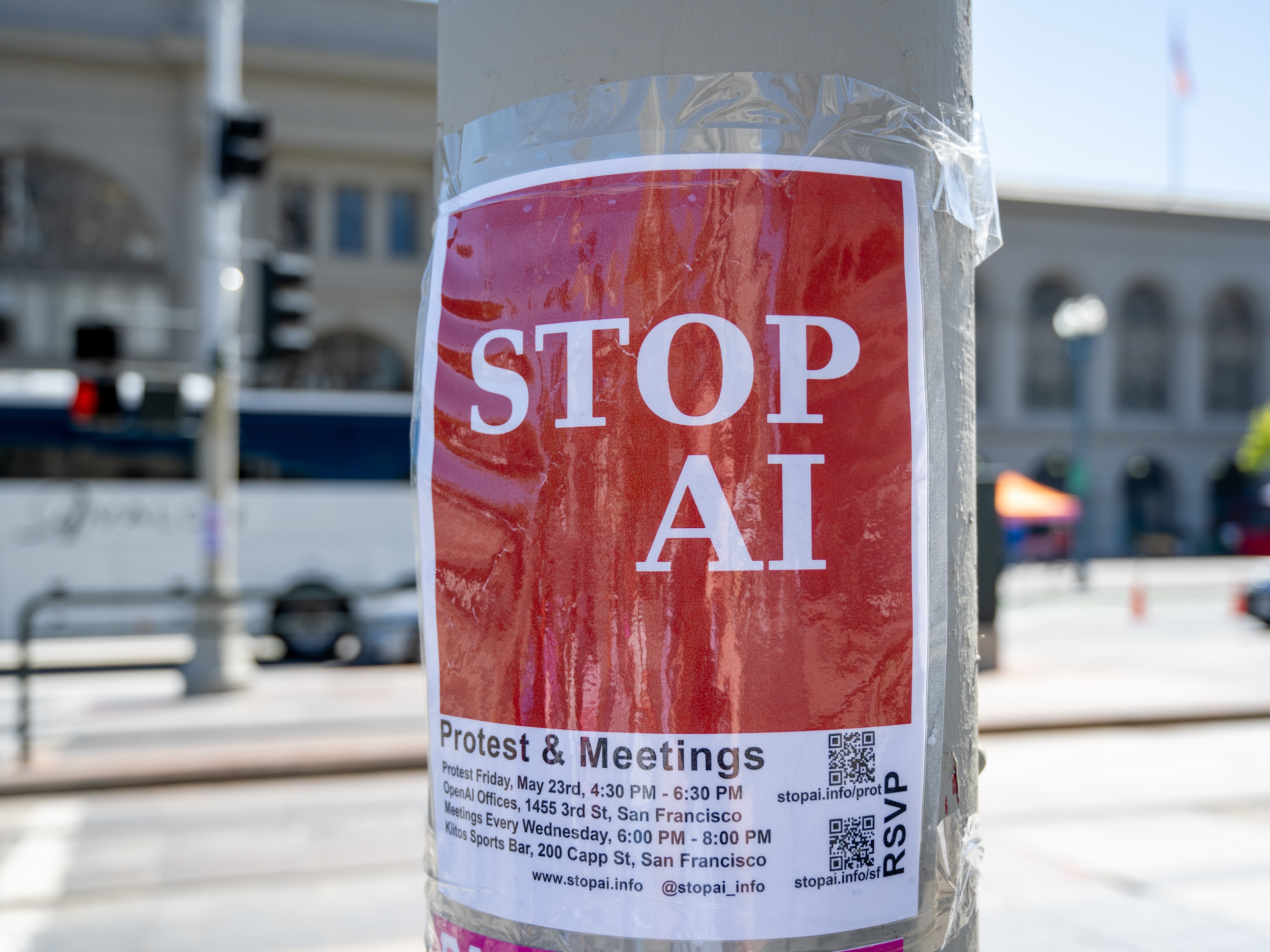 caption: Red STOP AI protest flyer with meeting details taped to a light pole on a city street in San Francisco, California on May 20, 2025.