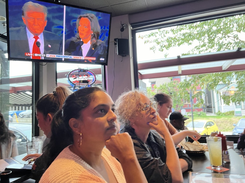caption: Sudha Nandagopal watches Vice President Kamala Harris debate former President Donald Trump at Rookie's in Columbia City on Sept. 10, 2024.