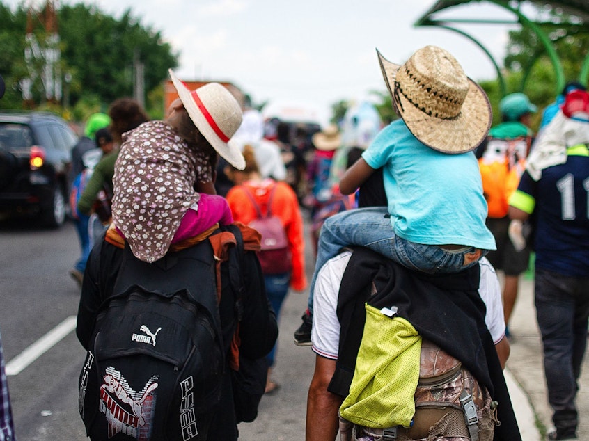 caption: Children are carried on the shoulders of Central American migrants heading to the U.S. along the road between Metapa and Tapachula, Mexico, on April 12. President Trump has called for measures to close what he calls the asylum "loophole" amid a spike in border crossings.