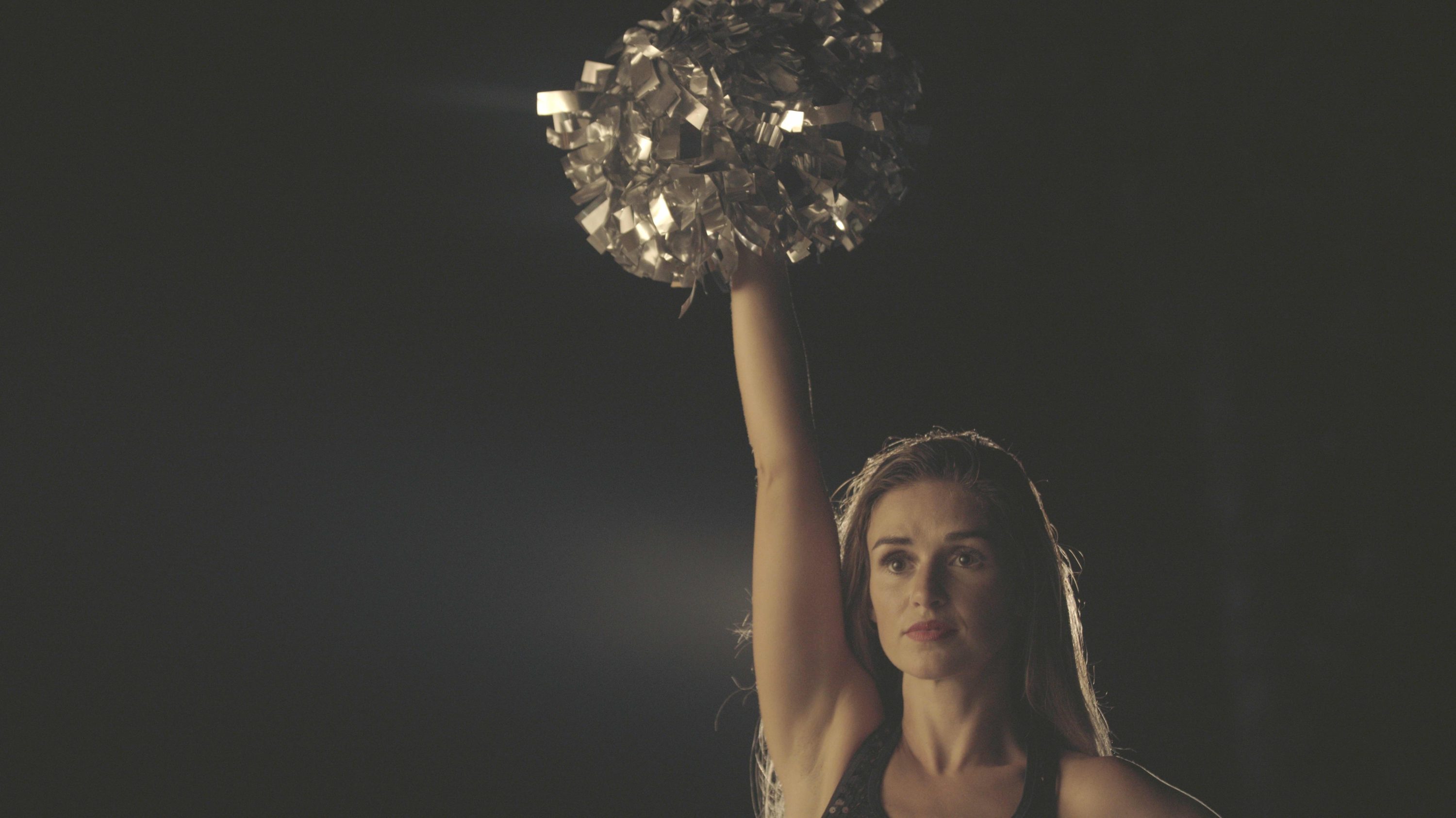 caption: Lacy Thibodeaux standing with pom poms in the air. (Photo by Yu Gu)