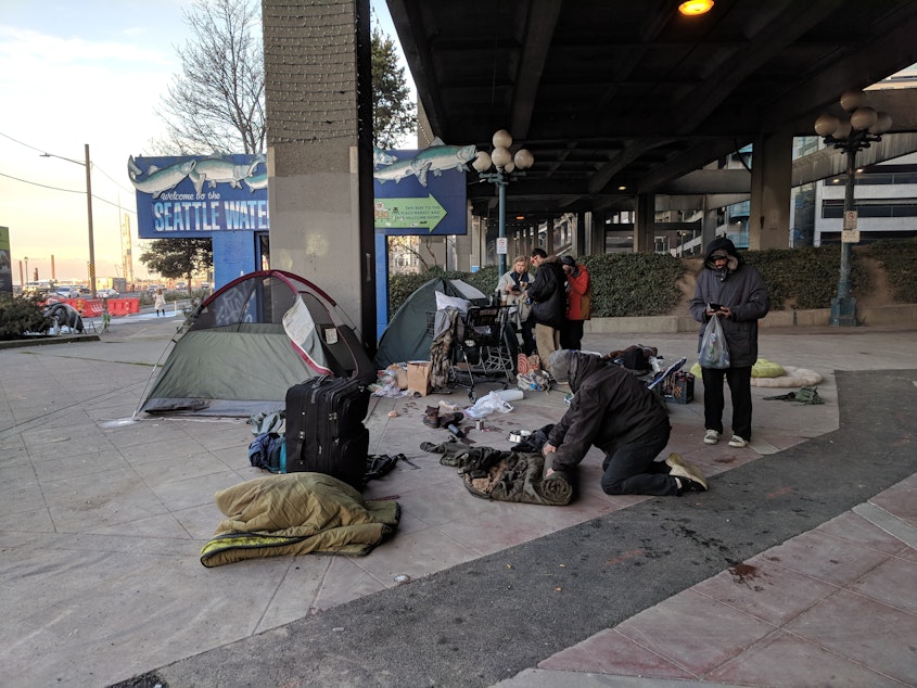 caption: Kenneth Liverman, far right, and his fellow campers prepare to move their tents from under the Alaskan Way Viaduct on Tuesday, January 15 2019. 