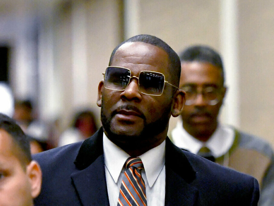 caption: R. Kelly, center, leaves the Daley Center after a hearing in his child support case in May 2019 in Chicago.